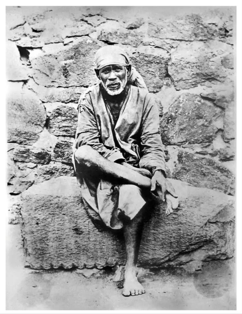 Original black and white photo of Shridi Sai Baba sitting on a rock